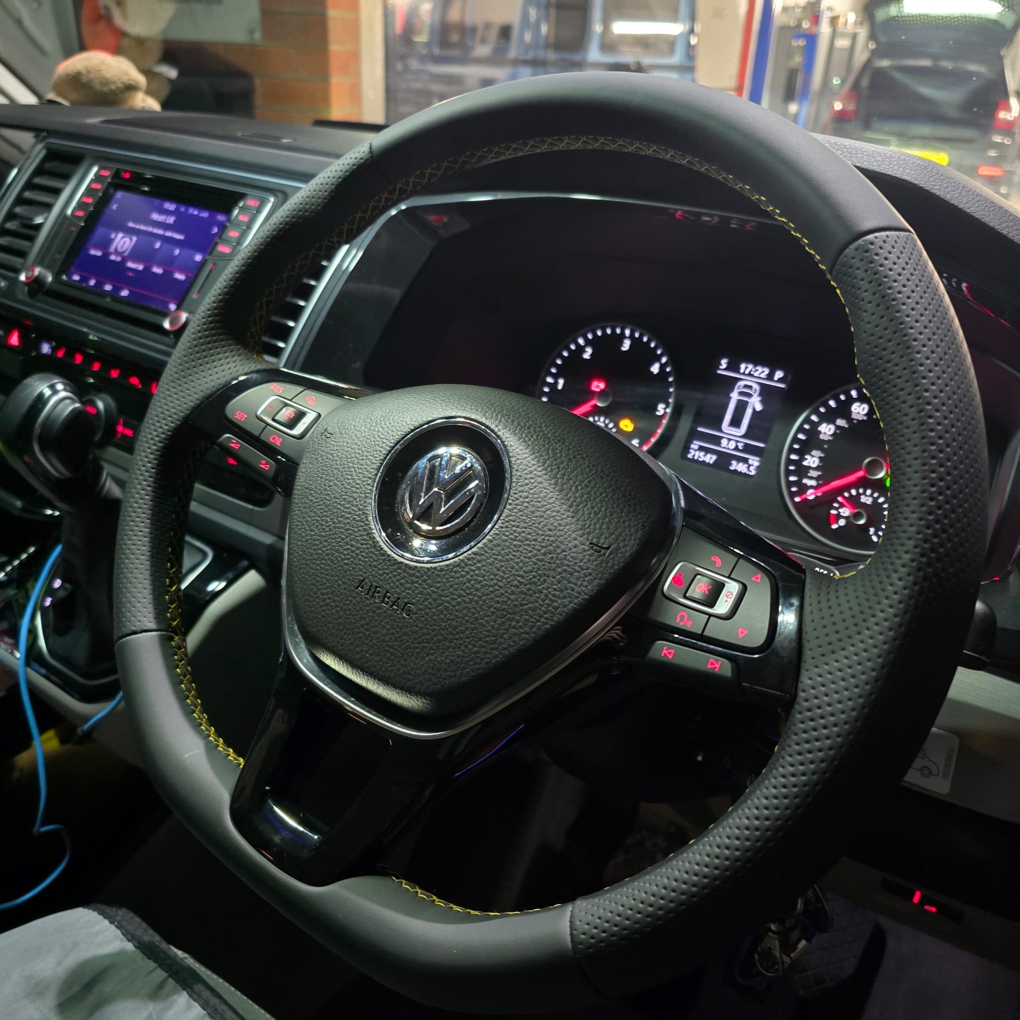 VW Transporter T6 steering wheel retrim detail showing yellow stitching perforated leather and multifunction buttons
